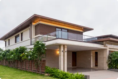 Modern two-story house with a glass balcony, brick and white exterior, and a covered entrance driveway.