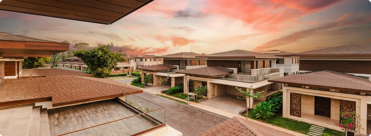 Sunset view over a modern townhouse complex with brown tiled roofs and green landscaping. (informative)