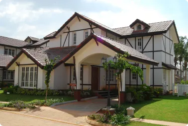 Two-story Tudor-style home with white walls, dark wooden trim, and a covered front entrance on a green lawn.