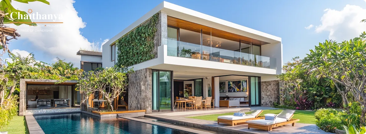Contemporary two-story villa with glass balcony, stone facade, and a rectangular pool surrounded by tropical landscaping and sun loungers.
